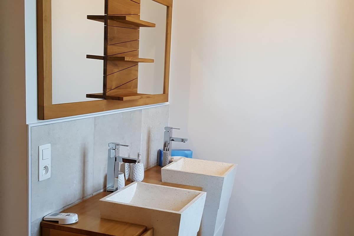 Ein modernes Badezimmer mit einem Holzbadezimmerhocker, zwei Waschbecken und einem großen Spiegel.