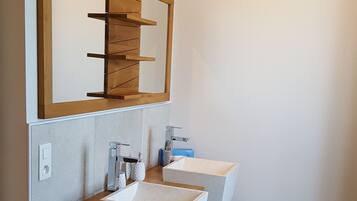 Een moderne badkamer met een houten wastafelmeubel, twee wastafels en een grote spiegel.