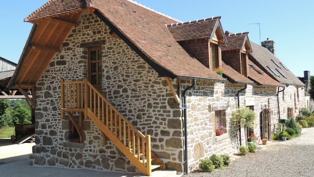 A stone building with a wooden staircase and a sloped roof. - Ferme Cidricole Hugues Desfrièches (Sainte-Marguerite-de-Carrouges)