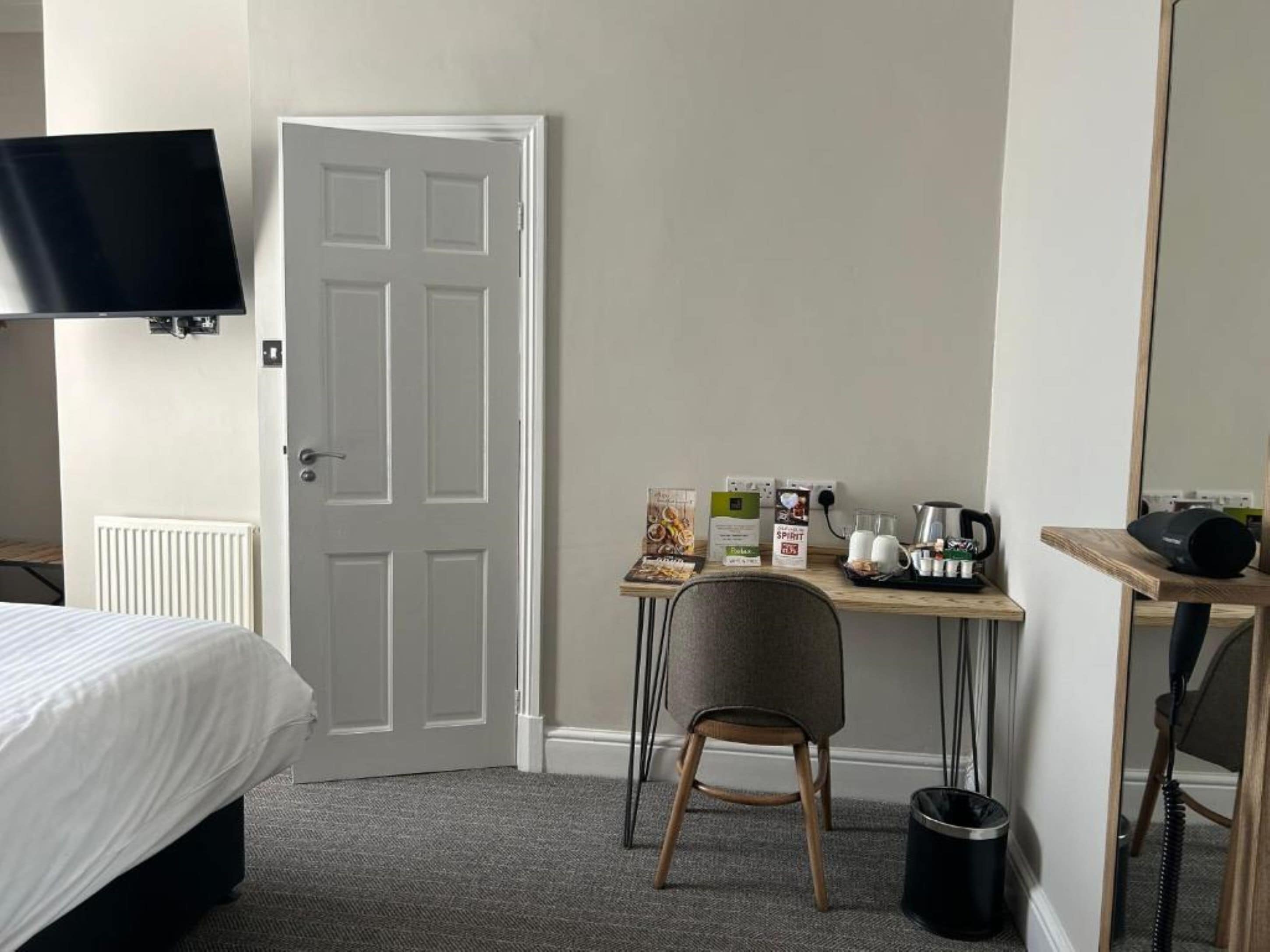 A hotel room with a bed, a desk with a chair, a television, and a coffee maker.