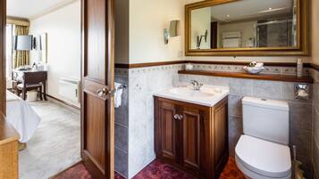 Un baño de hotel con un tocador de madera, un lavamanos, un inodoro y un espejo grande.