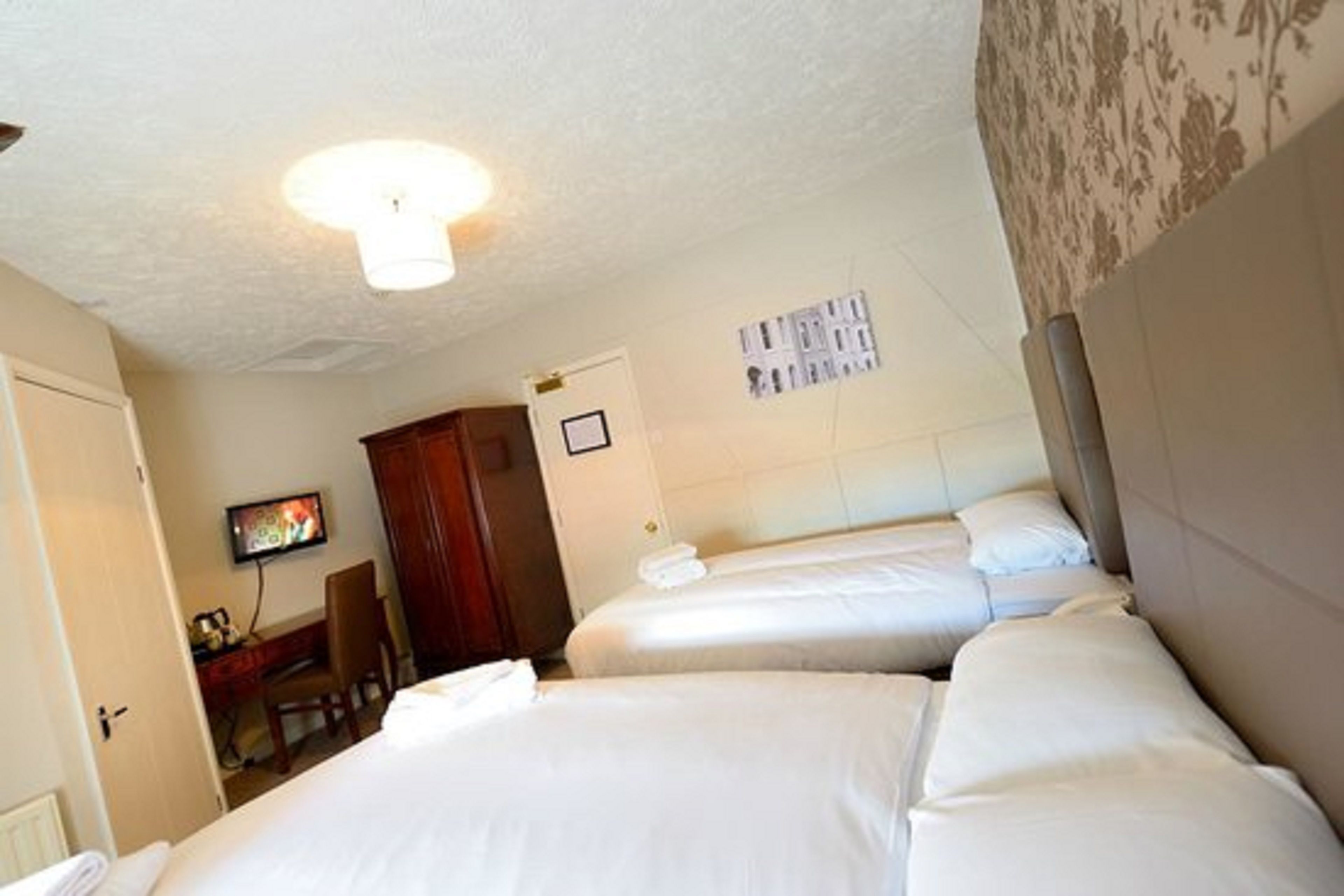 A hotel room with two beds, a television, a desk, and a chair.