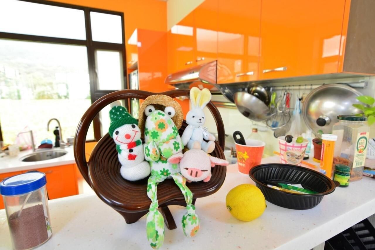 Una cocina con armarios color naranja, una silla de madera y varios utensilios de cocina, incluyendo un limón, un bol negro y un recipiente con azúcar.