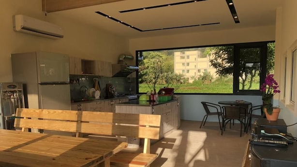 Une cuisine moderne avec une table à manger en bois, un banc et un téléviseur posé sur un meuble.