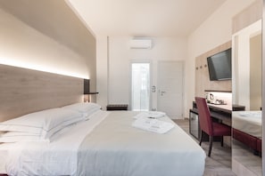 A hotel room with a bed, a desk, a chair, a television, and an air conditioning unit. - Le Nove Muse Guesthouse (Florence)