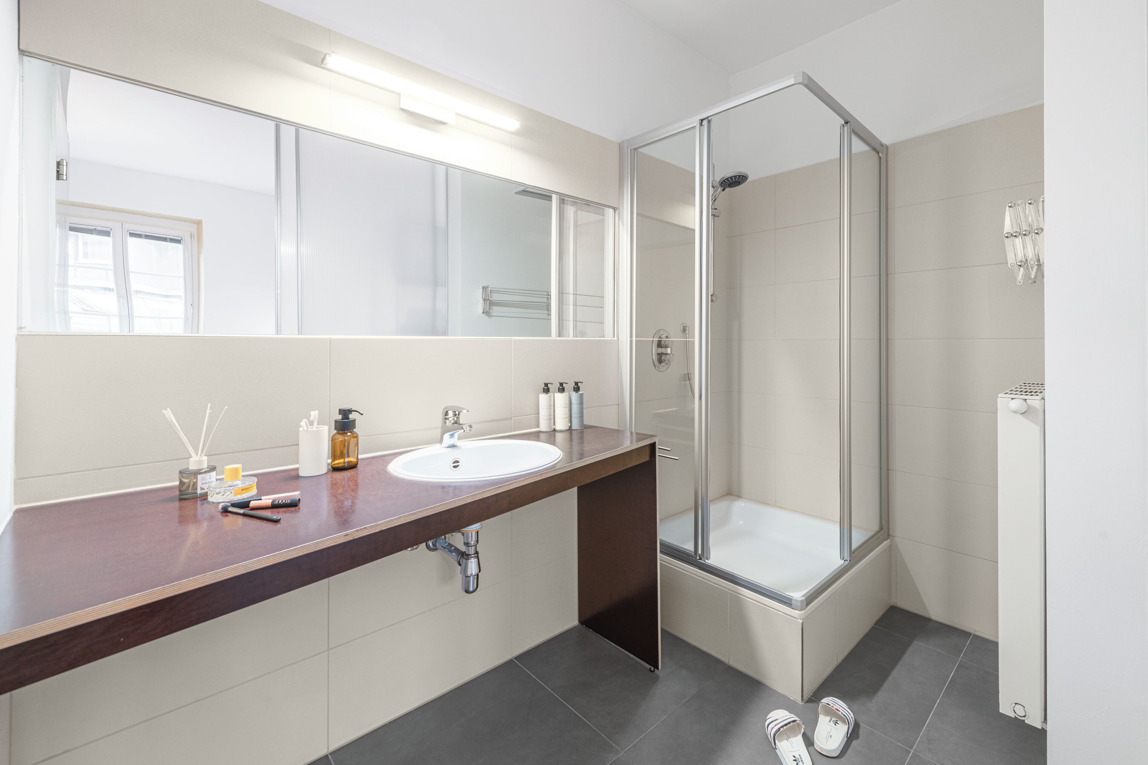 Un baño moderno con un espejo grande, un lavamanos y una ducha con mampara de vidrio.