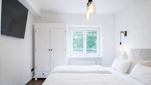 A bedroom with a large bed, a wardrobe, a window with a view of greenery, and a hanging light fixture. - Club Alpenresidenz Bad Gastein (Bad Gastein)