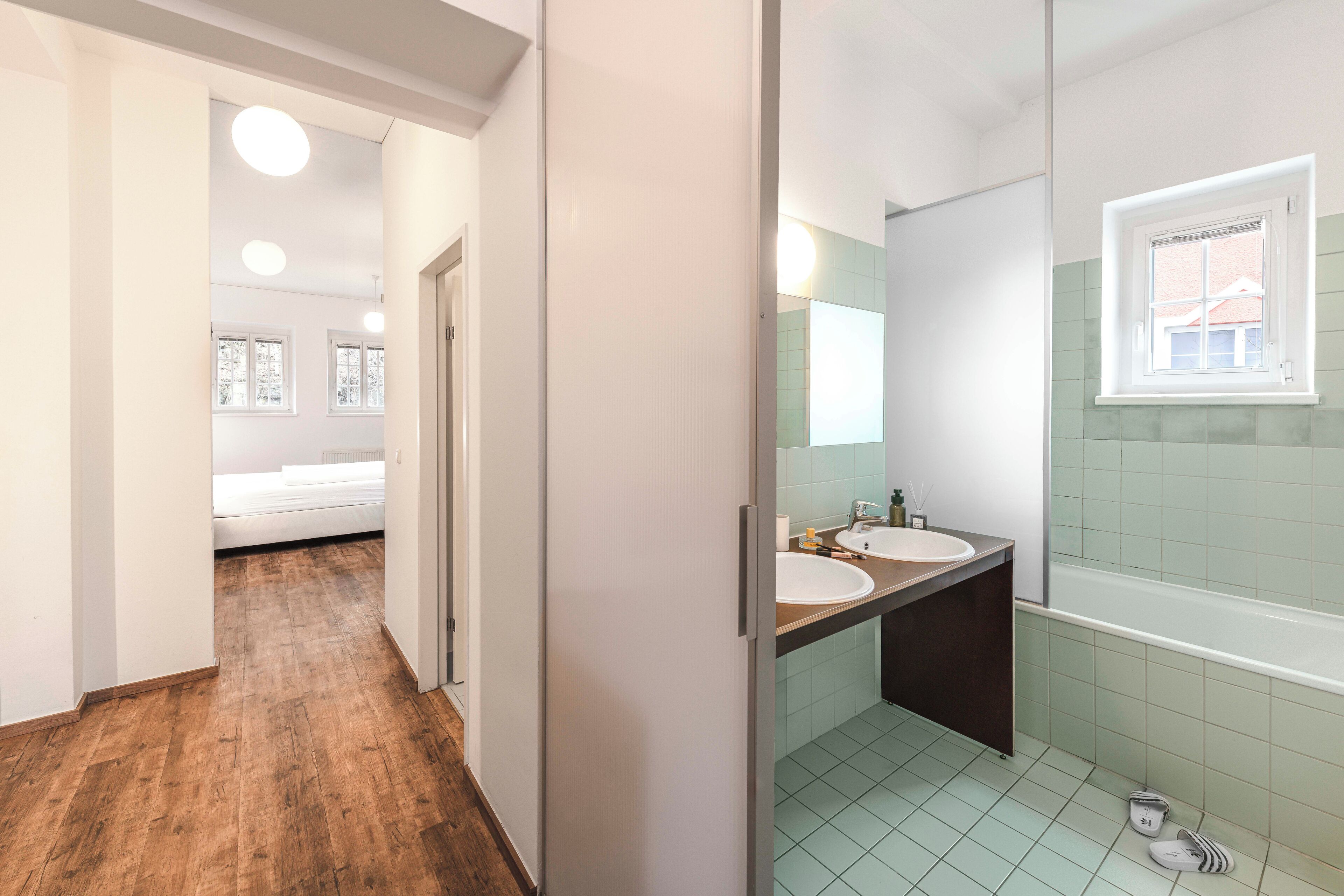 A modern bathroom with two sinks, a bathtub, and a window.