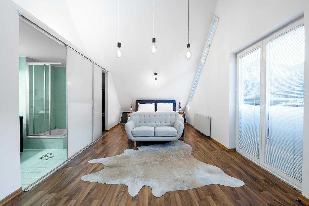 Ein modernes Schlafzimmer mit einem großen Bett, Holzboden und einem Fellteppich.