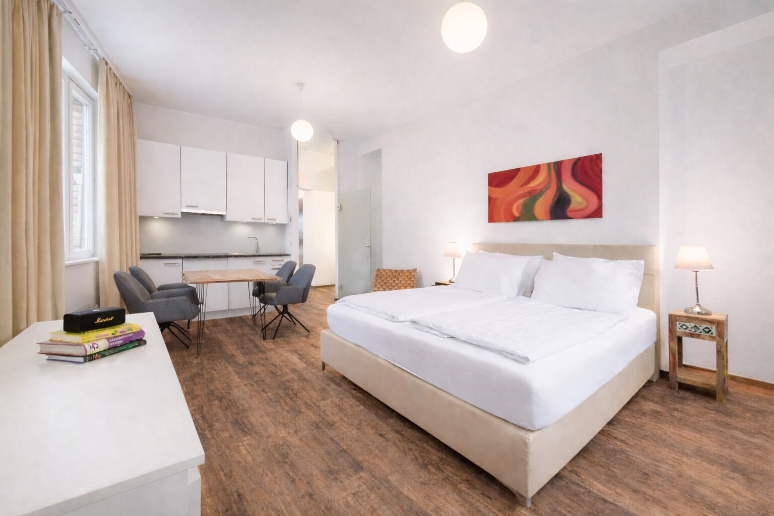 Habitación de hotel con cama, escritorio, sillas y un área de cocina.