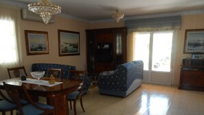 Un comedor con mesa y sillas de madera, un sofá azul y una araña.