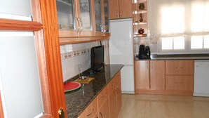Una cocina con armarios de madera, un refrigerador y un microondas.