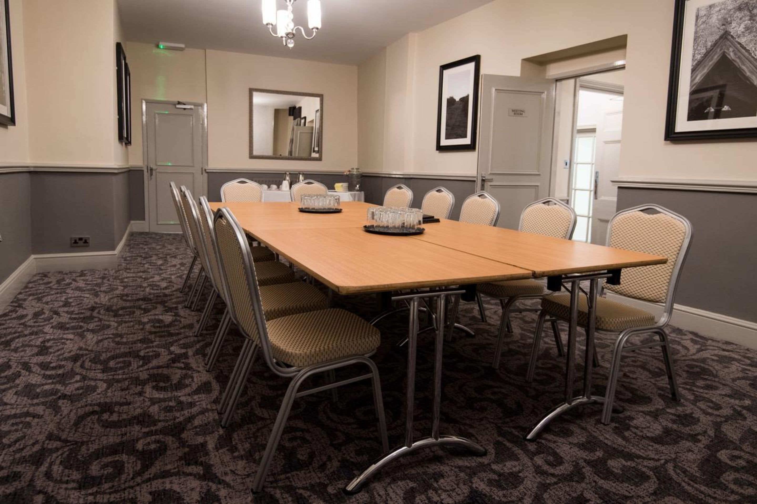 A conference room with a long table, chairs, and a carpeted floor.