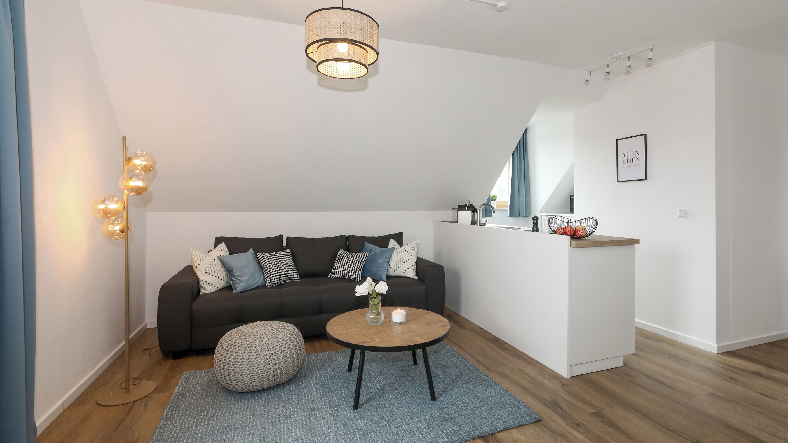 A modern living room with a dark sofa, a round coffee table, a floor lamp, and a pendant light.