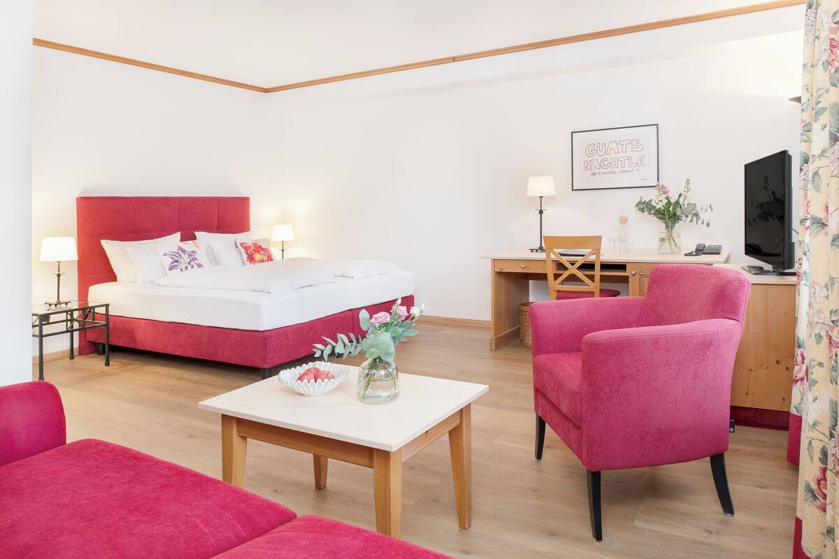 A bedroom with a bed, bedside tables, a desk, a chair, and a TV.