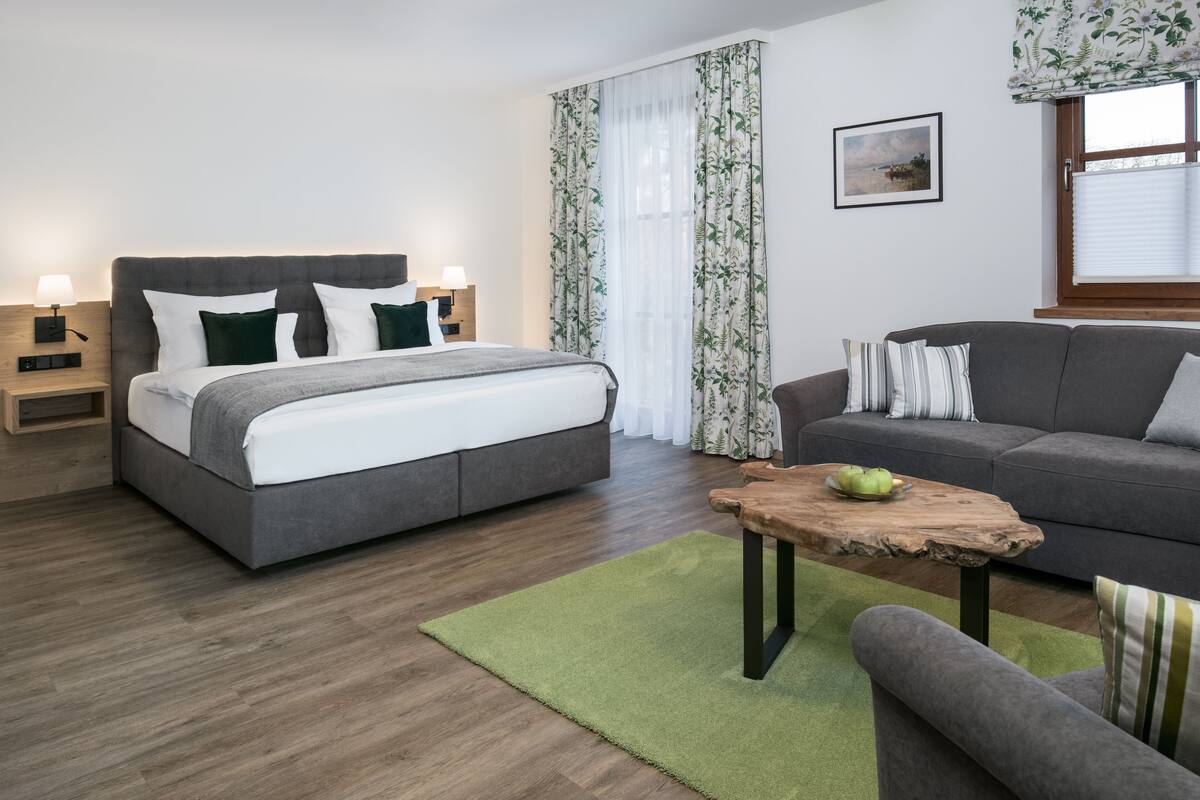 A modern bedroom with a bed, bedside tables, a wooden coffee table, and a grey sofa.