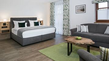 Quarto moderno com cama, mesas de cabeceira, uma mesa de centro de madeira e um sofá cinzento.