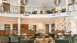 A spacious lobby with a central seating area, a reception desk, and a staircase connecting two floors.