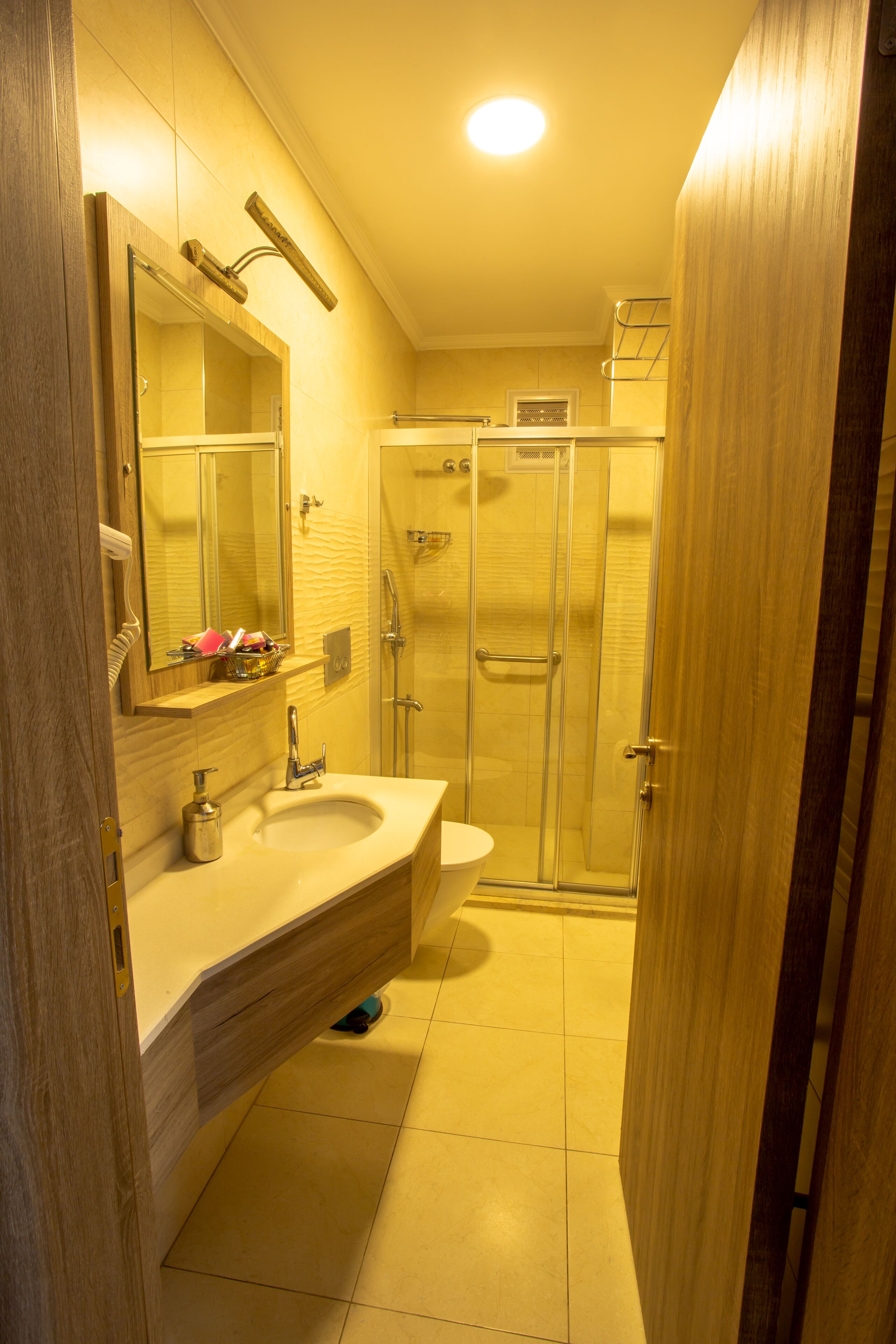 A bathroom with a wooden vanity, a sink, a mirror, a shower enclosure, and a toilet.