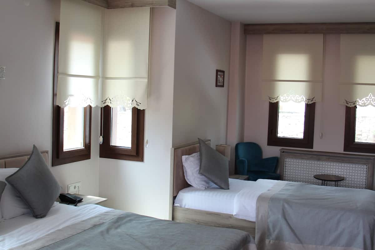 A hotel room with two beds, a small table, and a chair.