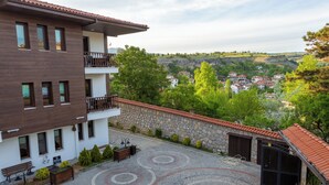 A multi-story building with a balcony, a paved courtyard with circular patterns, and a view of a town in the background. - Hıdırlık Konakları (Safranbolu)