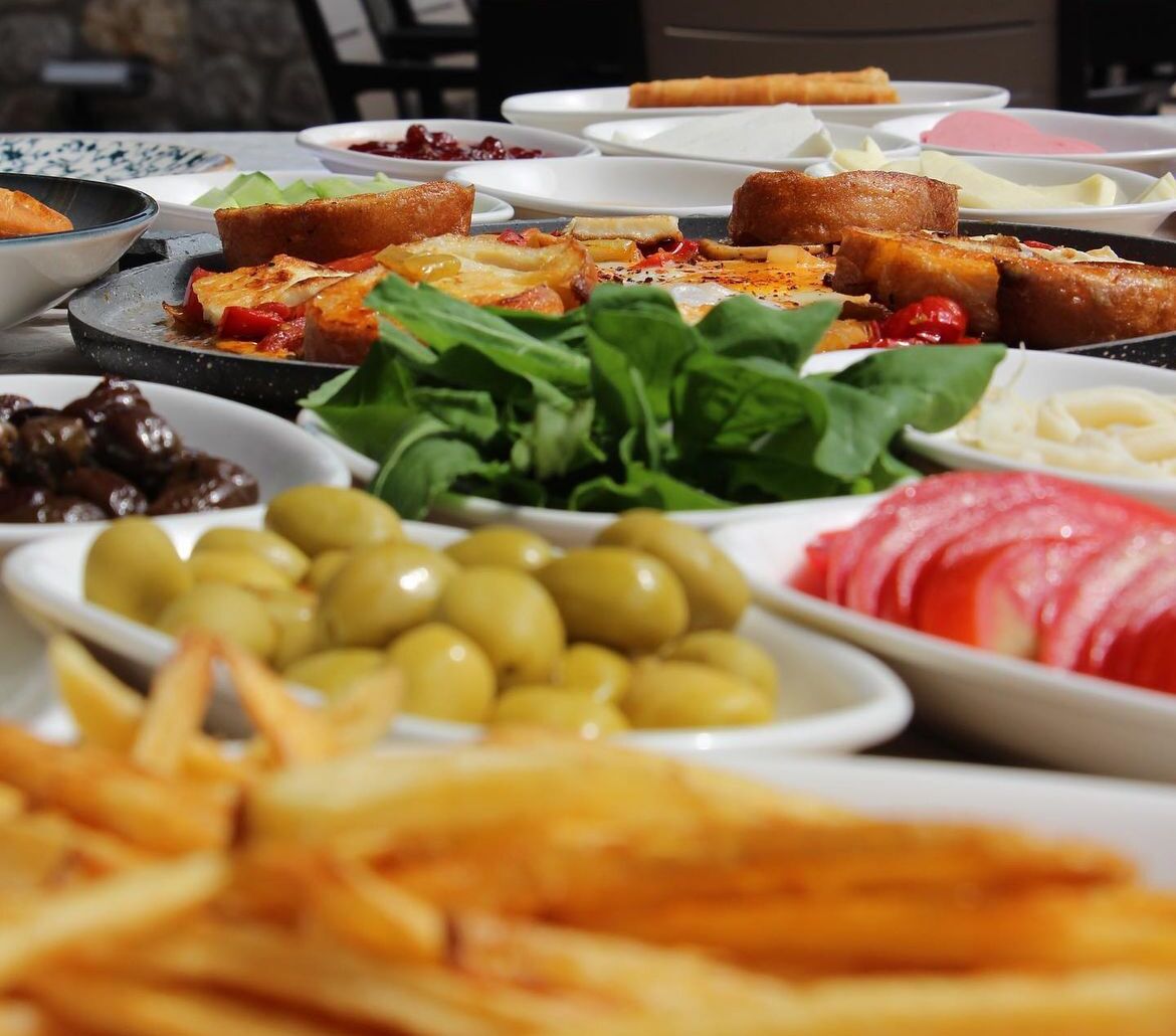 A variety of dishes including olives, greens, and bread, suggesting a meal setting.