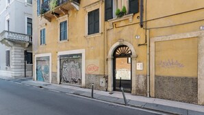 Un bâtiment doté d’un portail métallique fermé, d’une petite entrée en forme d’arc et d’une enseigne portant le chiffre « 7 ».
