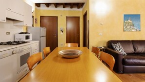 Une cuisine avec des appareils électroménagers blancs, une table à manger avec des chaises, un canapé en cuir marron et un tableau accroché au mur.