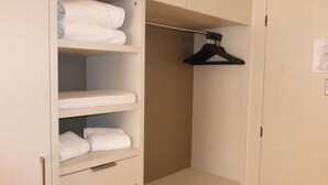 Een kast met planken, bezaaid met opgevouwen handdoeken en een zwarte ophanger.
