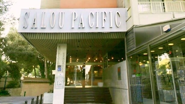 De ingang van Salou Pacific, met een bord boven de deur, een trap die omhoog leidt en een parkeersbord.