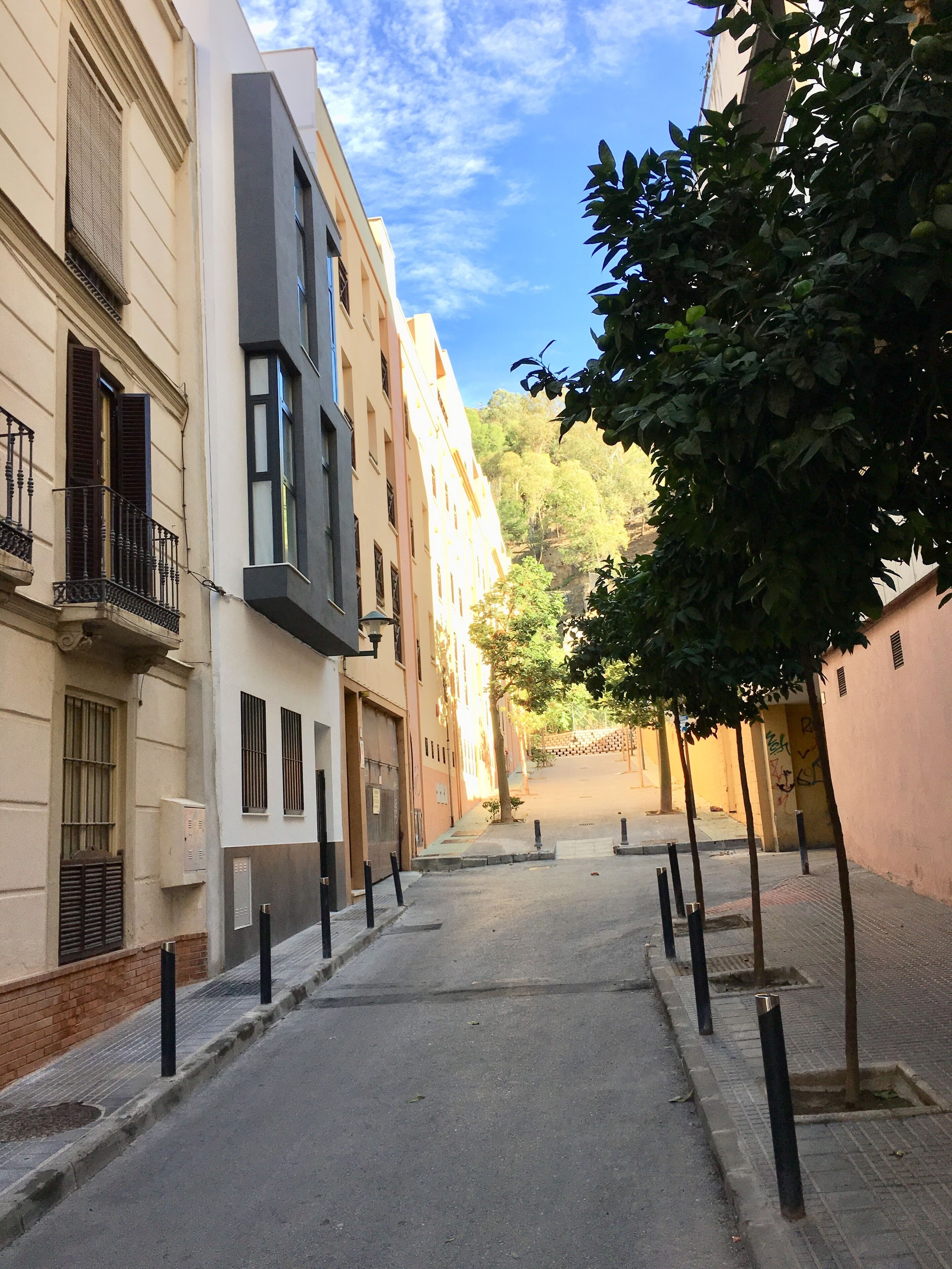 A narrow urban street flanked by multi-story buildings with balconies and windows.