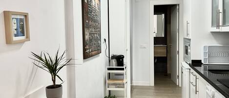 Una cocina moderna con armarios blancos, horno empotrado y lavadora.