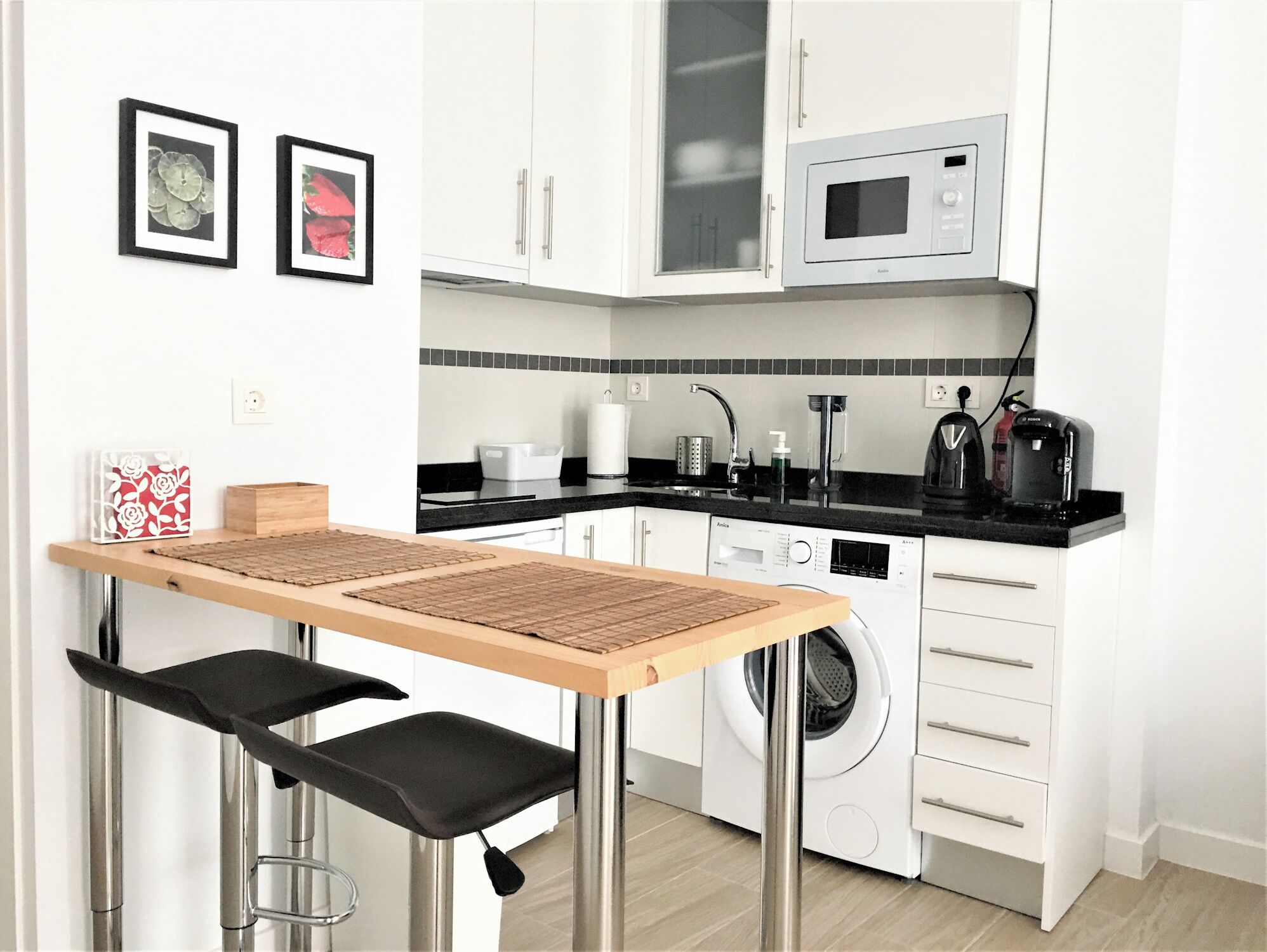 A compact kitchen with a washing machine, microwave, and a coffee maker.