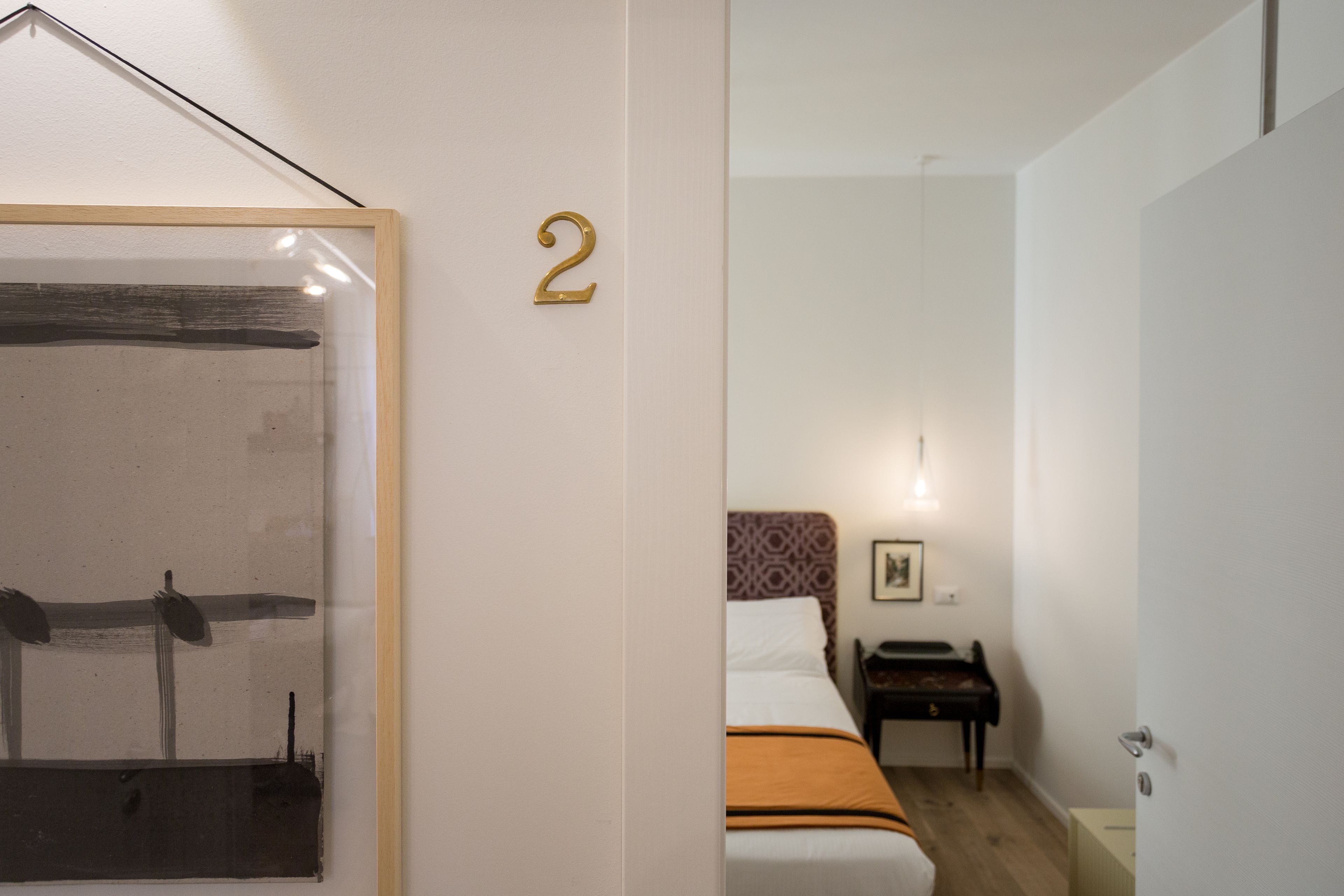 A hotel room with a bed, a piano, and a framed artwork on the wall.