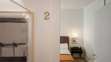 A hotel room with a bed, a piano, and a framed artwork on the wall.
