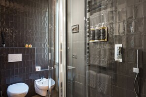 Un baño moderno con inodoro, bidé y cabina de ducha con mampara de vidrio.