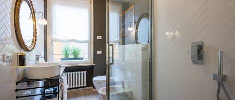A modern bathroom with a glass shower enclosure, a white sink, and a large mirror.