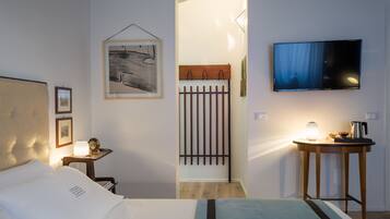 Una camera d'albergo con un letto, una scrivania con una lampada, una TV e un quadro appeso al muro.