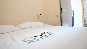 Ett hotellrum med en säng, ett eluttag och en dörr.