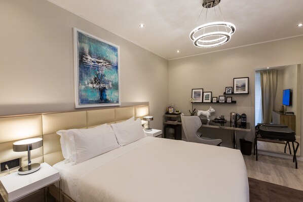 A hotel room with a large bed, bedside tables, a desk, a chair, a television, and a painting on the wall. - Clementi Portrait (Rome)
