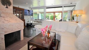 A modern living room with a fireplace, white sofa, and a television mounted on the wall. - Bay of Lübeck, Scharbeutz, holiday house 50 m to the beach (Scharbeutz)
