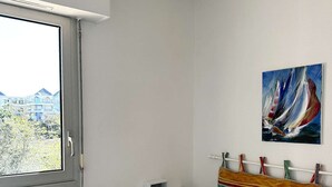 A bedroom with a bed, a window, a painting, and a radiator.