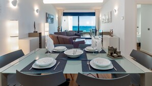A modern dining area with a glass table, chairs, and plates set for a meal. - The Links I 2226 Golf & Sea views (La Alcaidesa)