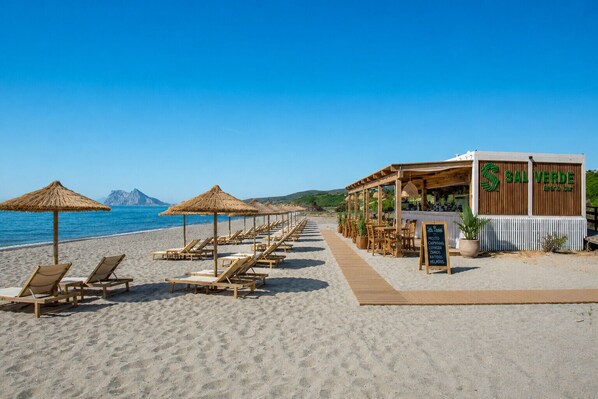 A beachside restaurant with outdoor seating, a wooden deck, and a signboard listing menu items. - The Links I 2226 Golf & Sea views (La Alcaidesa)