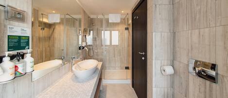 Un baño moderno con un lavamanos grande, cabina de ducha con mampara de vidrio y puerta de madera oscura.