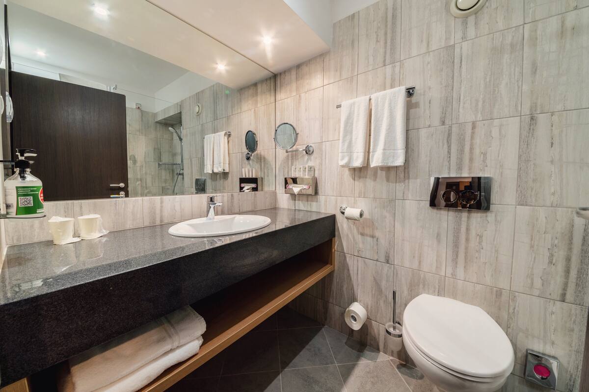 A modern bathroom with two sinks, a toilet, and a shower.