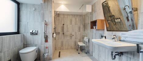 A modern bathroom with a toilet, shower, and sink.