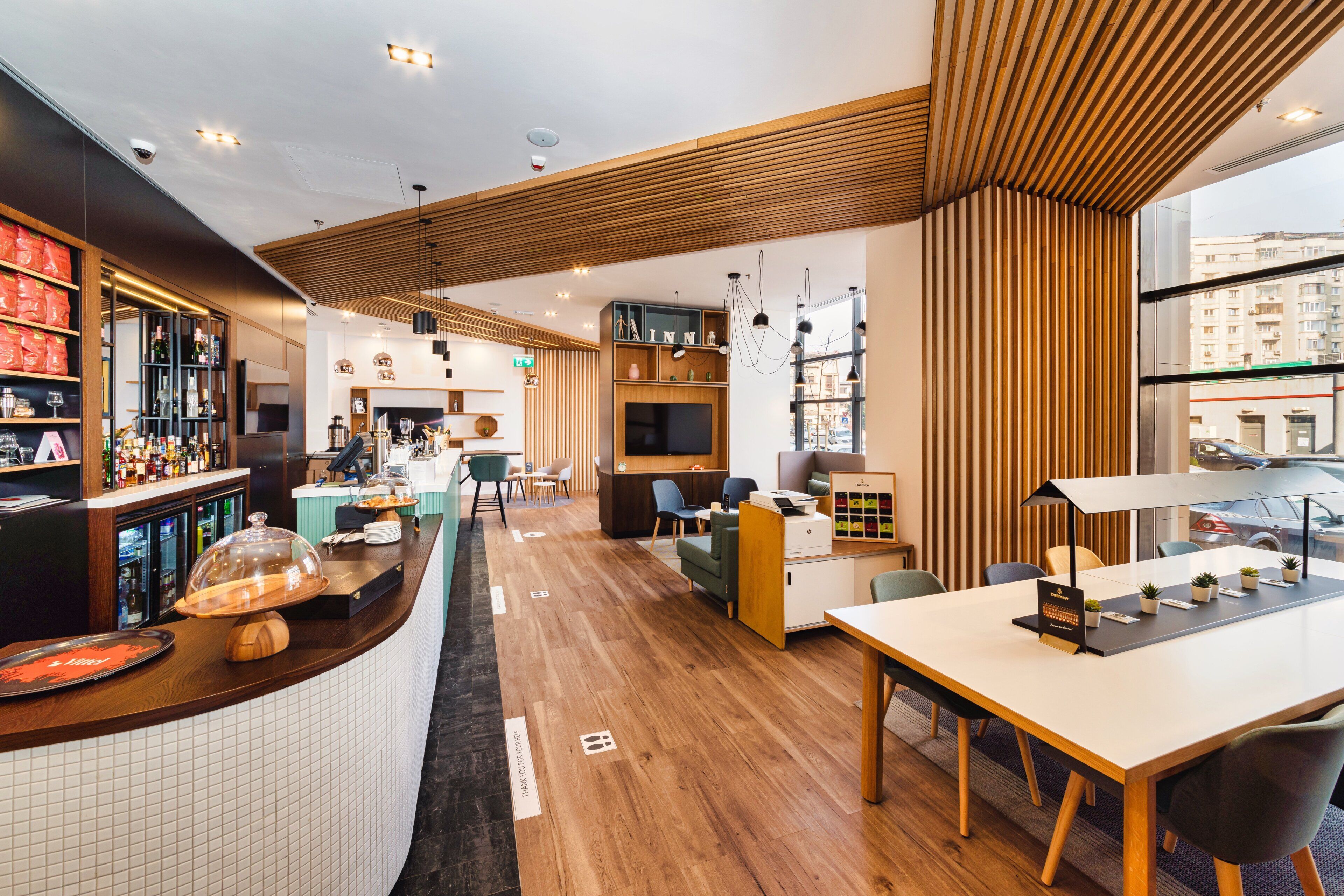 Un hall d’hôtel moderne doté d’un bar, de coins salon et d’un comptoir d’accueil.