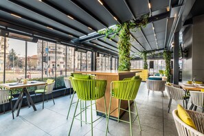 A modern outdoor seating area with green chairs and a wooden counter. - Holiday Inn Bucharest - Times by IHG (Bucharest)