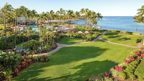 A resort with a pool, palm trees, and a view of the ocean. - Fairmont Orchid Gold Experience (Kamuela)